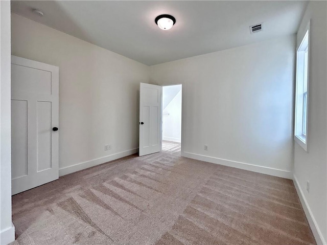 unfurnished room with carpet floors, visible vents, and baseboards