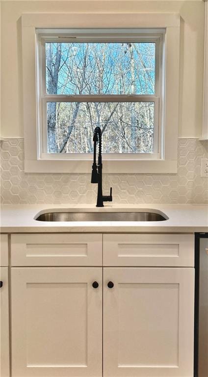 kitchen with light countertops, a sink, and white cabinets