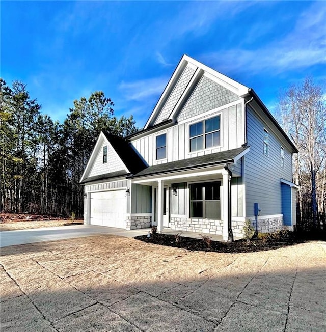 view of front of home featuring an attached garage, stone siding, board and batten siding, and concrete driveway