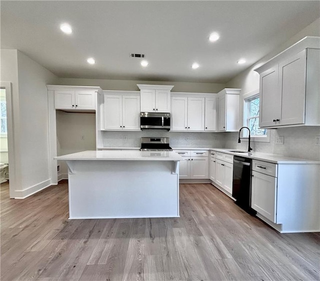 kitchen with visible vents, backsplash, appliances with stainless steel finishes, white cabinetry, and a sink