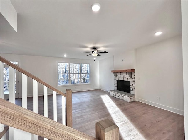 unfurnished living room featuring ceiling fan, recessed lighting, a fireplace, wood finished floors, and baseboards