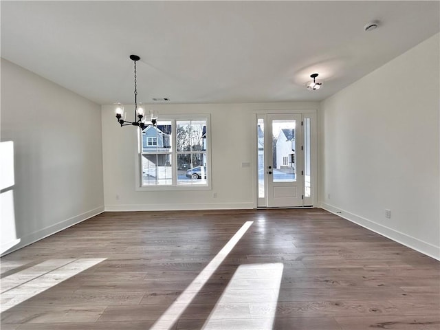 entrance foyer with a chandelier, wood finished floors, and baseboards