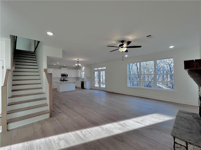 unfurnished living room with stairs, light wood finished floors, visible vents, and recessed lighting