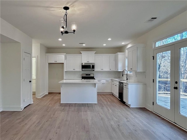 kitchen featuring light wood-style flooring, stainless steel appliances, backsplash, and french doors