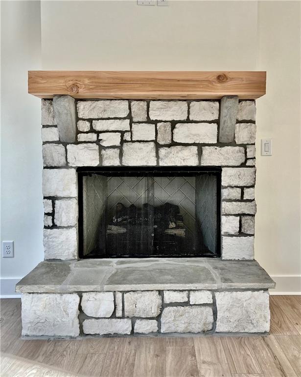 room details with a stone fireplace, wood finished floors, and baseboards