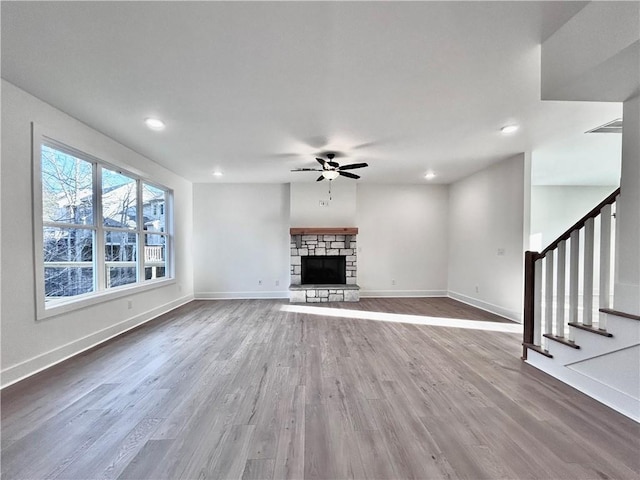 unfurnished living room featuring stairs, a fireplace, baseboards, and wood finished floors