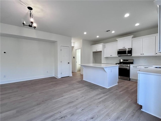 kitchen featuring light wood finished floors, white cabinets, a kitchen island, stainless steel appliances, and light countertops