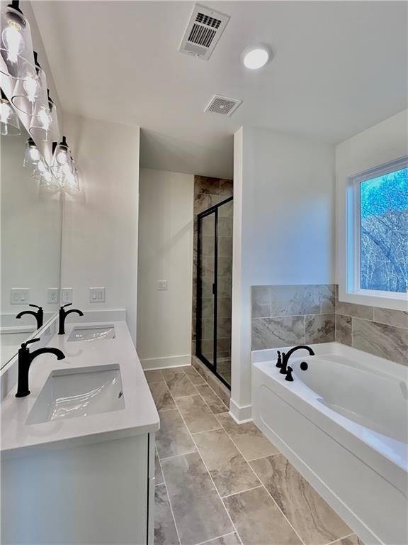 bathroom with a garden tub, visible vents, a sink, and a stall shower