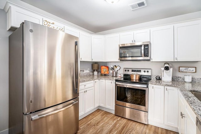 kitchen featuring light wood finished floors, appliances with stainless steel finishes, visible vents, and white cabinetry