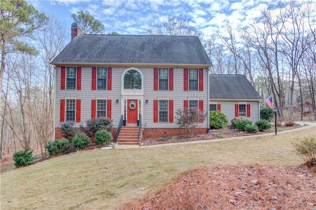 colonial house featuring a chimney and a front yard