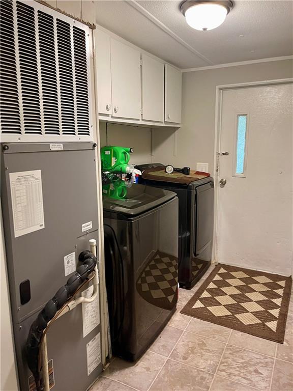 laundry room with cabinets, separate washer and dryer, heating unit, ornamental molding, and light tile patterned floors