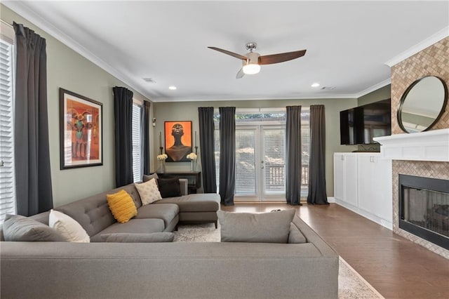 living room with crown molding, hardwood / wood-style flooring, a fireplace, and ceiling fan