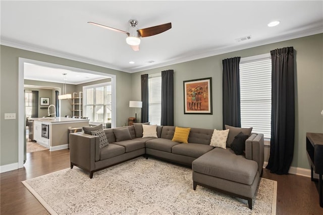 living room featuring ornamental molding, sink, dark hardwood / wood-style floors, and ceiling fan