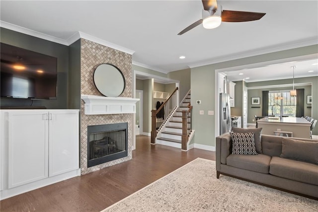 living room with ornamental molding, ceiling fan, a fireplace, and dark hardwood / wood-style flooring