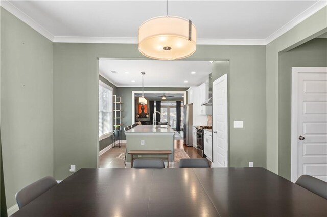 dining area with crown molding, sink, and hardwood / wood-style floors