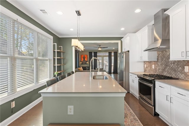 kitchen featuring wall chimney exhaust hood, sink, white cabinets, and stainless steel appliances