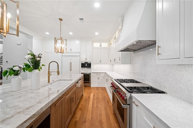 115 Baxley Ln, Alpharetta, GA 30004 - kitchen with light stone counters, light wood-style flooring, premium range hood, appliances with stainless steel finishes, and a sink