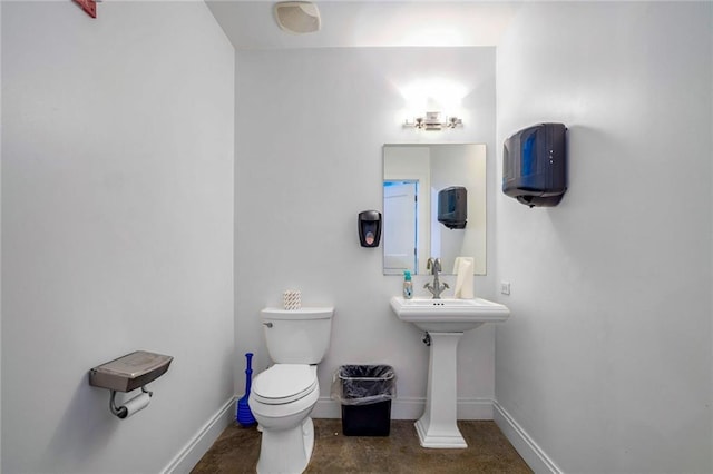 half bath featuring baseboards and toilet