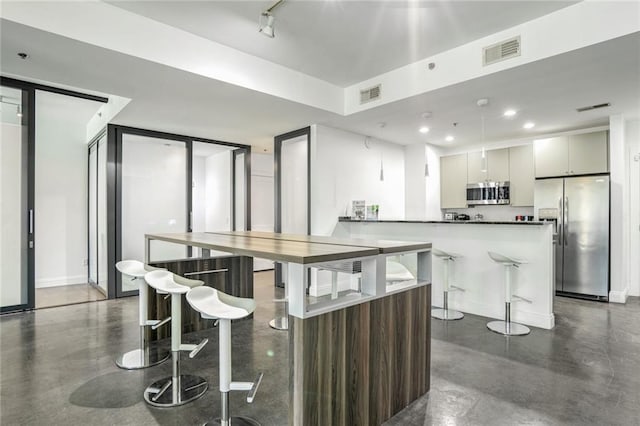 kitchen with stainless steel appliances, a peninsula, visible vents, and a breakfast bar area