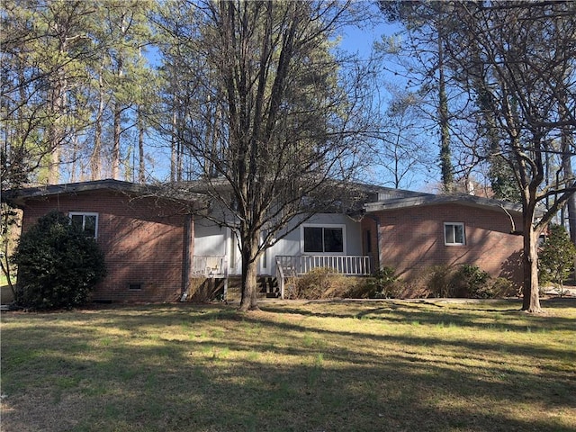 exterior space with crawl space, a porch, a front lawn, and brick siding