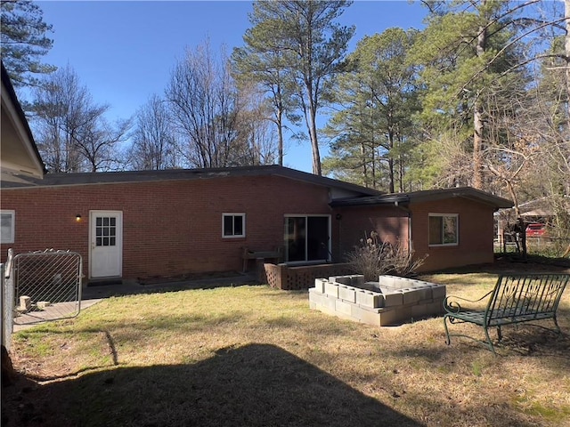 back of house featuring brick siding and a lawn