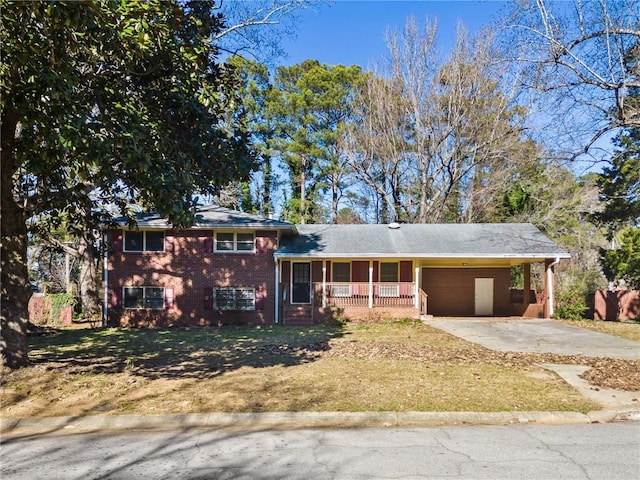 split level home with covered porch, a front yard, and a carport