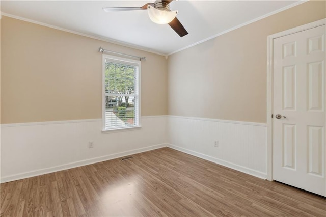 spare room with ceiling fan, light wood-type flooring, and ornamental molding