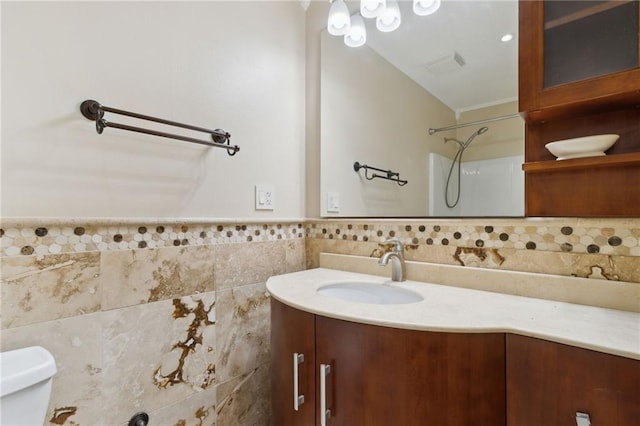 bathroom with walk in shower, vanity, tile walls, and toilet