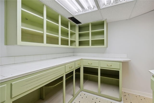 interior space featuring a drop ceiling and green cabinetry