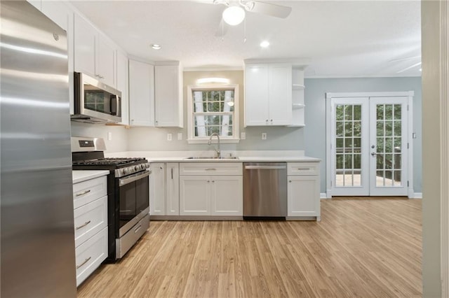 kitchen with light wood-type flooring, white cabinetry, stainless steel appliances, and a wealth of natural light