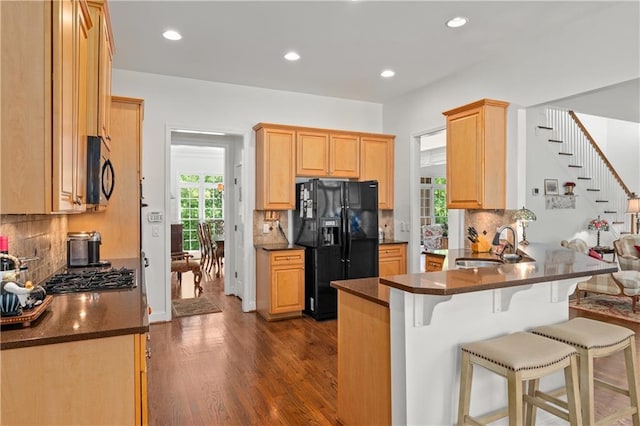 5725 Lake Oak Lndg, Cumming, GA 30040 - kitchen with black appliances, dark countertops, a sink, dark wood finished floors, and a breakfast bar area