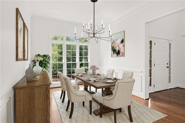 5725 Lake Oak Lndg, Cumming, GA 30040 - dining space with a decorative wall, a chandelier, ornamental molding, wood finished floors, and wainscoting