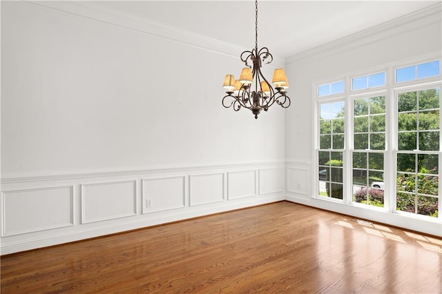 5725 Lake Oak Lndg, Cumming, GA 30040 - unfurnished dining area with crown molding, a chandelier, a wainscoted wall, wood finished floors, and a decorative wall