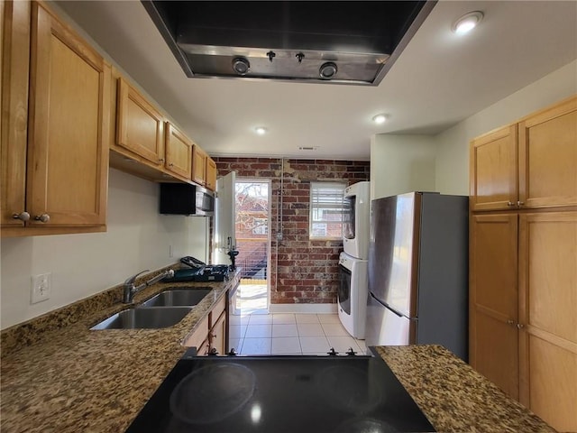 40 Daniel St SE Unit 7, Atlanta, GA 30312 - kitchen with a sink, dark stone counters, freestanding refrigerator, brick wall, and stacked washer and clothes dryer