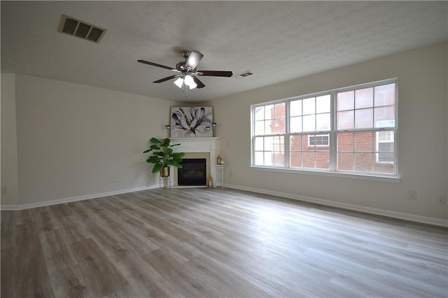 unfurnished living room featuring ceiling fan, a textured ceiling, and light hardwood / wood-style flooring