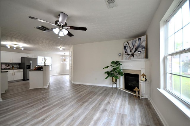 unfurnished living room with light hardwood / wood-style floors, a textured ceiling, and ceiling fan