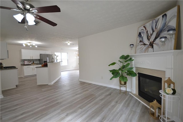 living room featuring a textured ceiling, light hardwood / wood-style floors, and ceiling fan