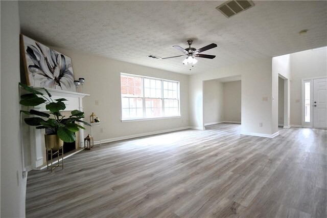 unfurnished living room featuring a textured ceiling, hardwood / wood-style flooring, a fireplace, and ceiling fan