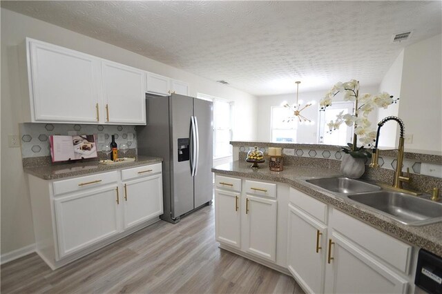 kitchen featuring sink, white cabinetry, light hardwood / wood-style floors, an inviting chandelier, and stainless steel refrigerator with ice dispenser