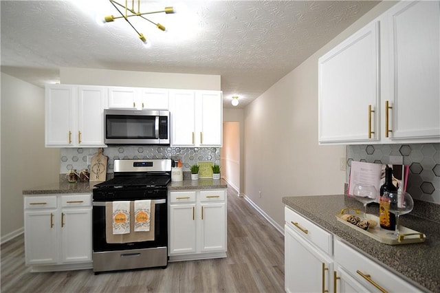 kitchen with decorative backsplash, white cabinetry, a textured ceiling, light hardwood / wood-style flooring, and stainless steel appliances