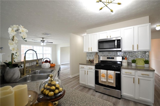 kitchen with appliances with stainless steel finishes, white cabinetry, and sink