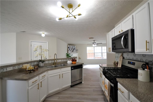 kitchen with a textured ceiling, white cabinets, and stainless steel appliances