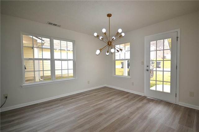 unfurnished dining area featuring a notable chandelier and wood-type flooring