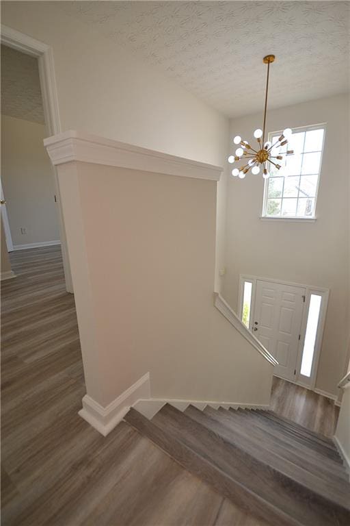 stairway with hardwood / wood-style floors, a chandelier, and a textured ceiling