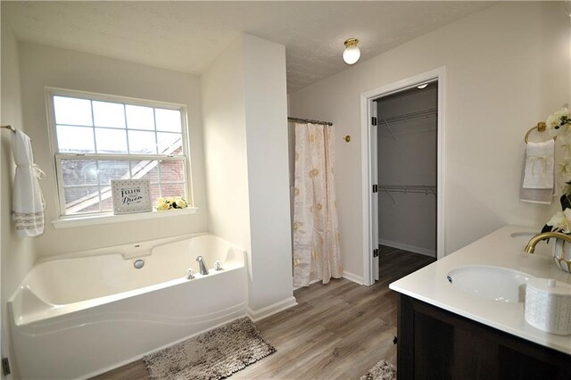 bathroom with vanity, a tub to relax in, a textured ceiling, and wood-type flooring