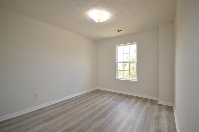 unfurnished room featuring a textured ceiling and light wood-type flooring