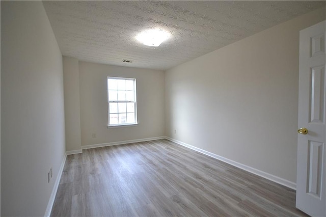 unfurnished room with light hardwood / wood-style floors and a textured ceiling