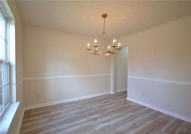 spare room featuring a chandelier, hardwood / wood-style flooring, and a textured ceiling