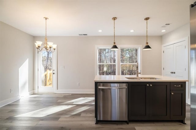 kitchen featuring pendant lighting, sink, stainless steel dishwasher, an island with sink, and a notable chandelier