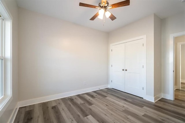 unfurnished bedroom with hardwood / wood-style floors, a closet, and ceiling fan